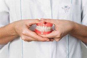 Dental team member holding full upper and lower dentures