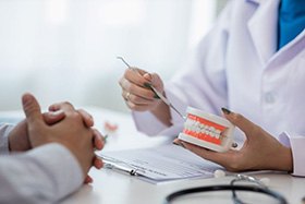 Dentist and patient sitting at desk, discussing treatment plan