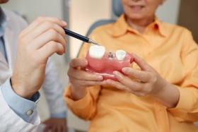 Showing a patient a model of a dental implant in Dallas, TX