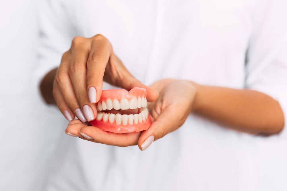 Hands holding a full denture