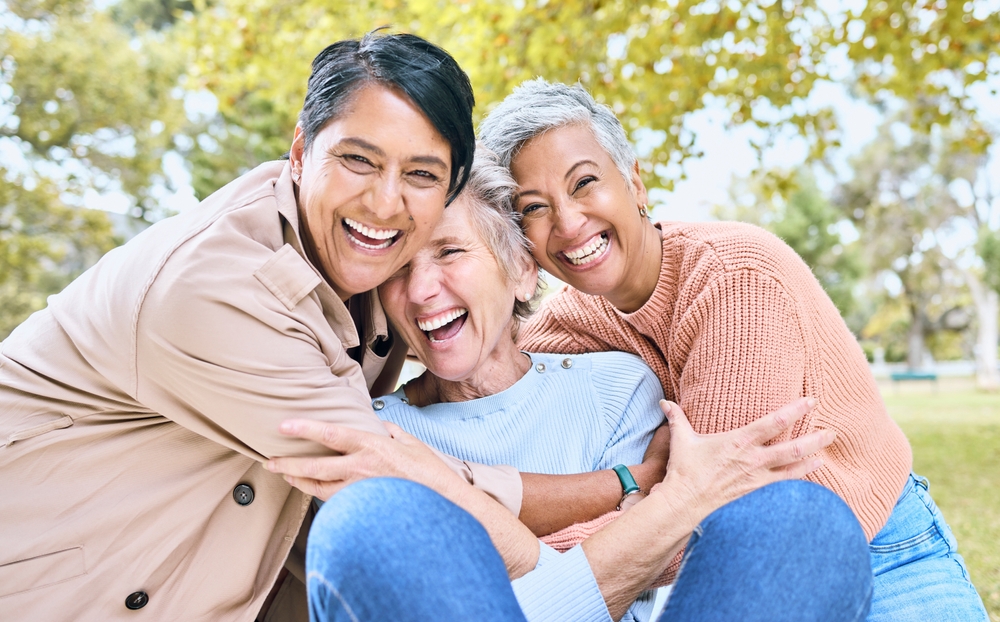 Three smiling women sitting together outdoors
