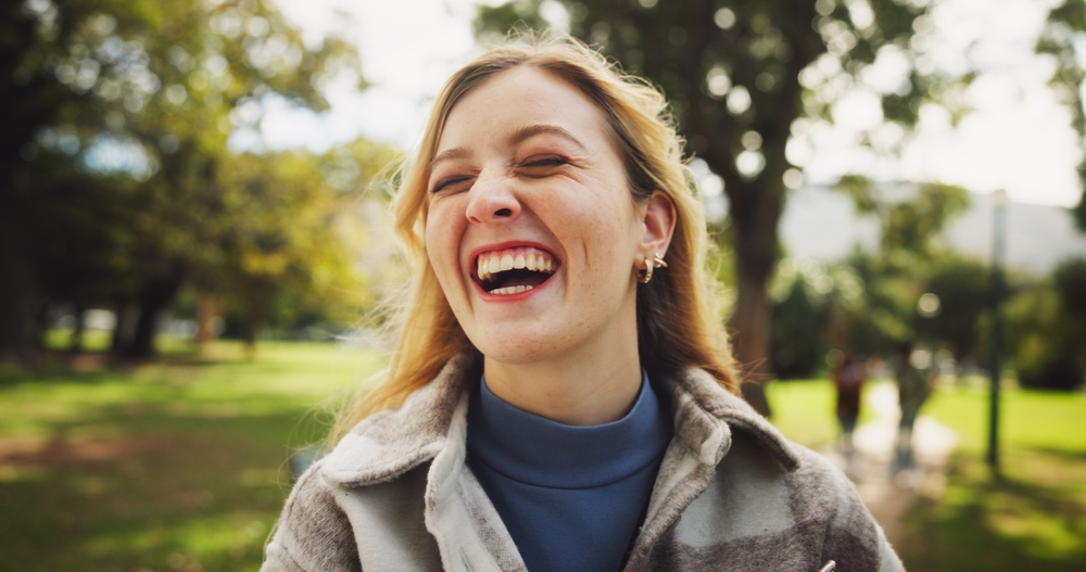 Young woman laughing outdoors with a bright smile