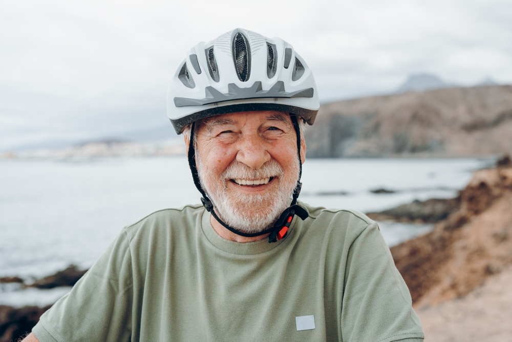 Smiling older man in a bicycle helmet by the sea