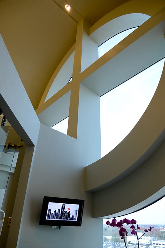 Office interior with a large round window and a wall-mounted TV